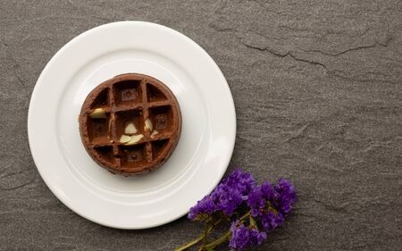 chocolate waffle with almond slide on a white plate, purple flower, fresh baked for sweet meal, dessert concept.の写真素材