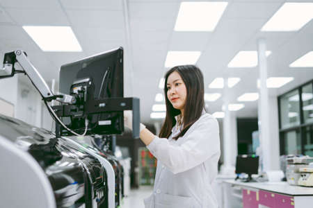 young female scientist working with automation blood analyzer report in medical laboratoryの写真素材