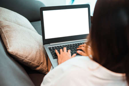 young woman working on laptop computer with blank background while sitting at the living room.