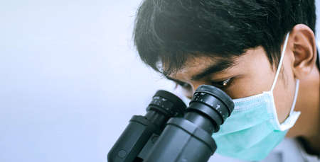 Close up young scientist looking at microscope