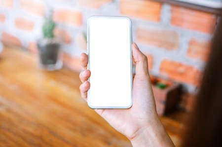young woman holding smart phone with blank screen while sitting at the living room