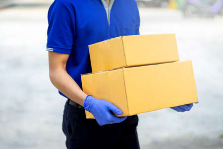 Delivery man put on gloves and masks to hold cardboard boxesの写真素材