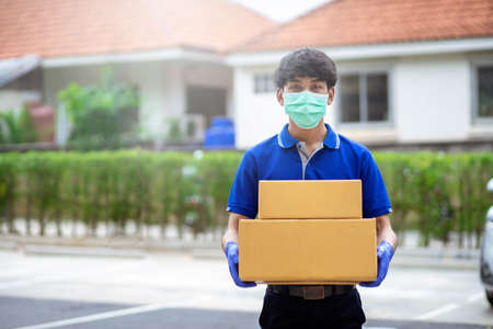 Delivery man put on gloves and masks to hold cardboard boxesの写真素材