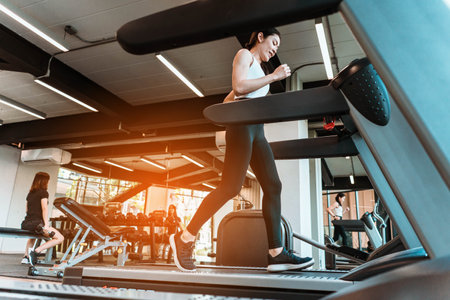 young sports woman is running treadmill in gym. Doing cardio training