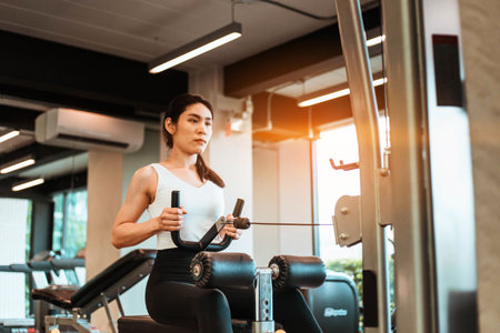 Young beautiful woman in sportswear working out with machine in gym