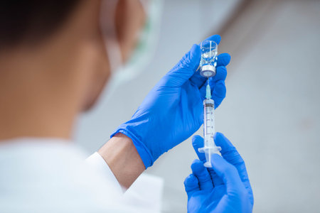 Doctor in blue glove filling syringe with vaccineの写真素材