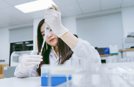 Young medical scientist working in medical laboratory , young female scientist using auto pipette to transfer sampleの写真素材