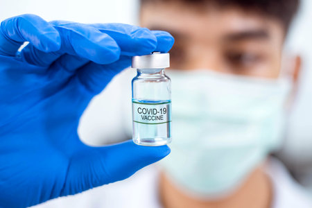 A  scientist in laboratory holding a bottle with liquid vaccinesの写真素材