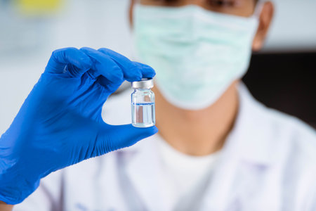 A  scientist in laboratory holding a bottle with liquid vaccinesの写真素材