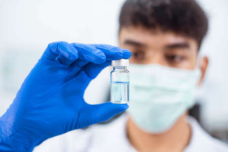 A  scientist in laboratory holding a bottle with liquid vaccinesの写真素材