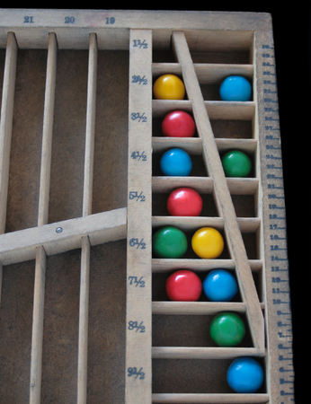 multicolored gumballs in a printer's quarter-size wood rule case