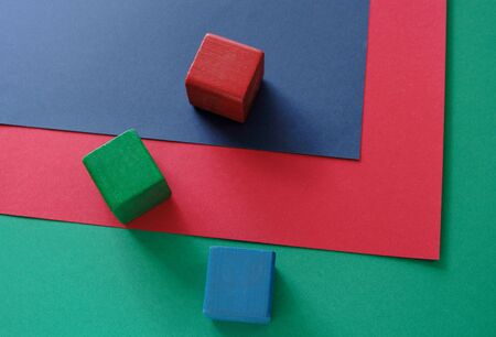 three blocks in red, green and blue on three sheets of red, green and blue paperの写真素材