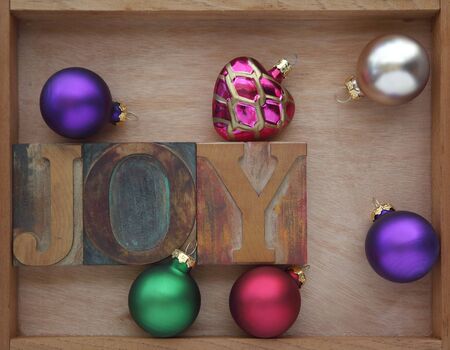 the word joy with Christmas ornaments in a wooden box