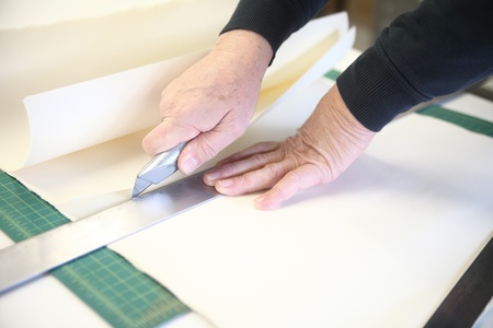 an older man cuts paper using a ruler and box cutter
