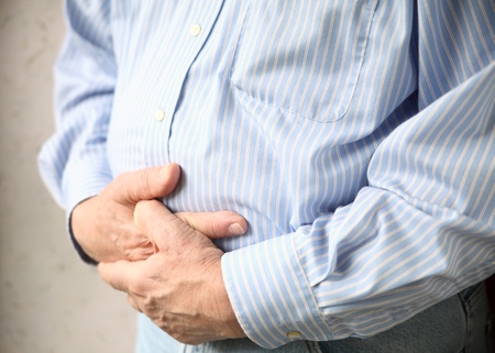 a man holds both hands to his stomachの写真素材