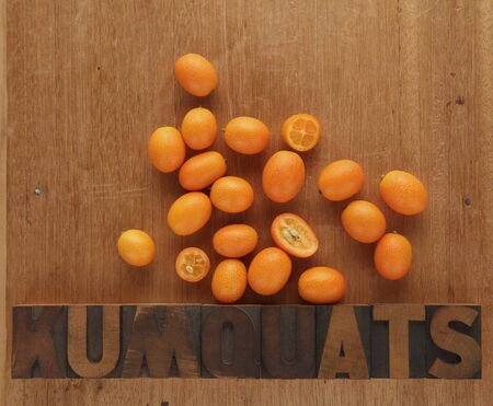 the word kumquats in old wood type with brightly-colored fruitsの写真素材