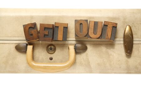 the words get out in old letterpress wood type on an old suitcaseの写真素材