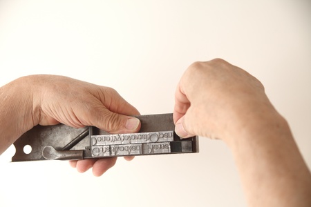 a printer adjusts letterpress metal type on a tool used to set typeの写真素材