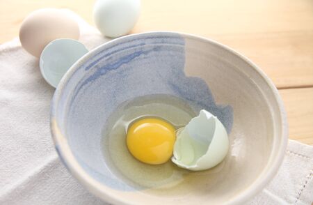 egg with naturally pastel-colored shell in a pottery bowlの写真素材