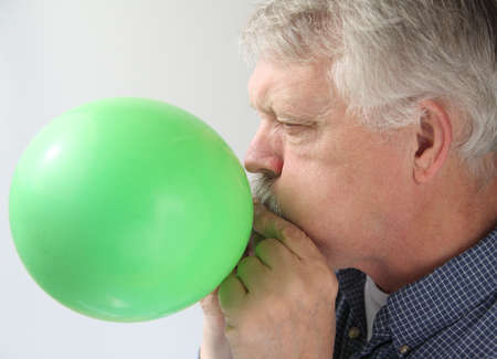 a man blows up a green balloonの写真素材