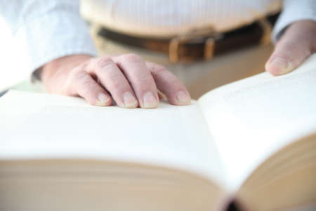 man with his hands on a large bookの写真素材