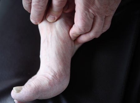 man s hands on his painful foot