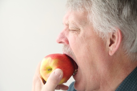 older man bites into an appleの写真素材