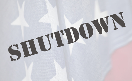 the word shutdown in a stencil font on an old USA flagの写真素材