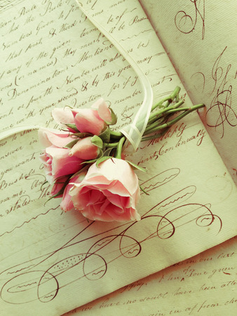 small bouquet of miniature roses on pages from an 18th century workbookの写真素材