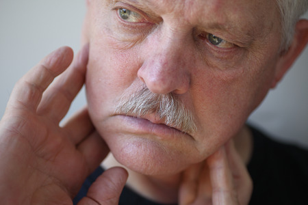 Senior man touches his sore jaw area の写真素材