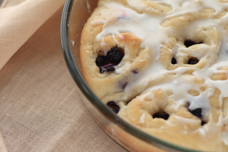 Fresh, homemade blueberry rolls with vanilla icing on a linen napkinの写真素材