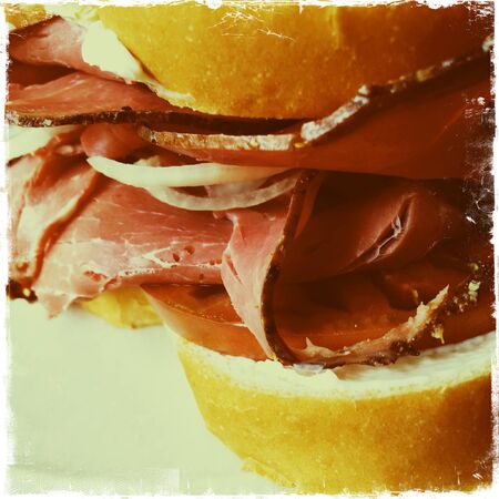 Closeup view of cured meat slices and tomato in a sandwichの写真素材