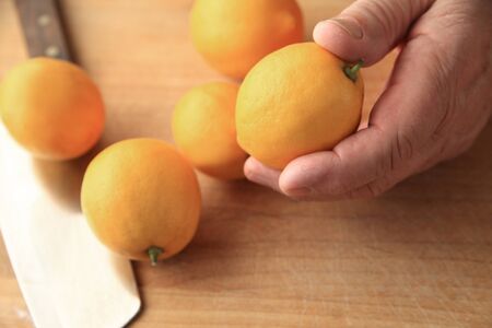 Several lemons on a cutting board, a man holding oneの写真素材