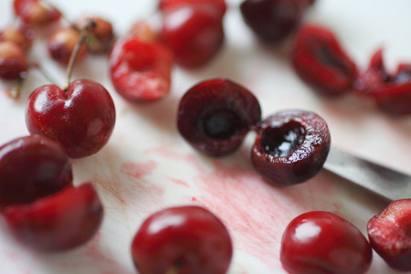 Removing pits from fresh cherries on white cutting boardの写真素材