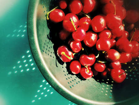 Red fruits with a shadow cast by an old colanderの写真素材