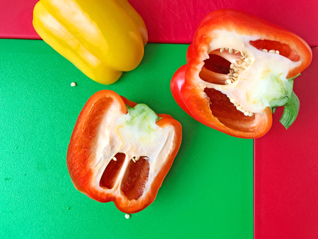 Yellow and red bell pepper halves on colorful cutting boards with room for textの写真素材