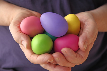 A man holds several brightly colored Easter eggsの写真素材