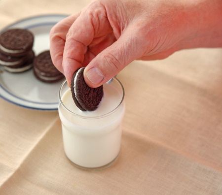 A man dips a cookie in a glass of milk with copy spaceの写真素材