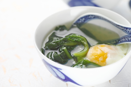 Malabar spinach soup with poached egg in Chinese bowl with spoon and copy spaceの写真素材