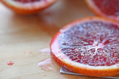 Closeup of a fresh slice of blood orange on a cutting boardの写真素材