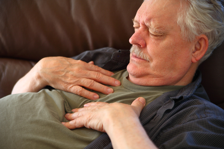 Older man experiences pain in his chest while lying downの写真素材