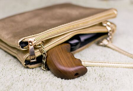 Female self-defense. A pistol peeping out of a woman's handbag.