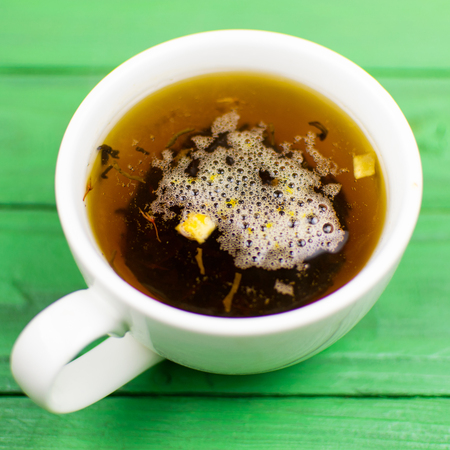 Tea in a white cup on a green wooden background.の写真素材