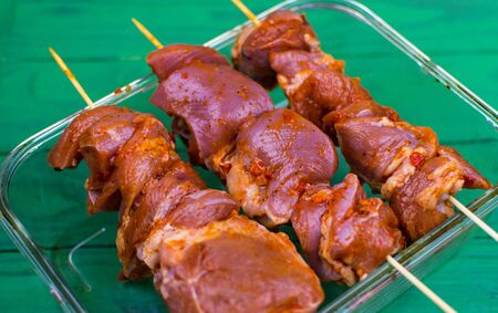 Pieces of marinated meat in seasonings on wooden skewers.の写真素材
