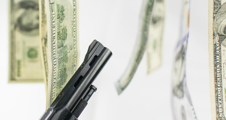 Pistol and money on a white background. The concept of crime is because of money.の写真素材