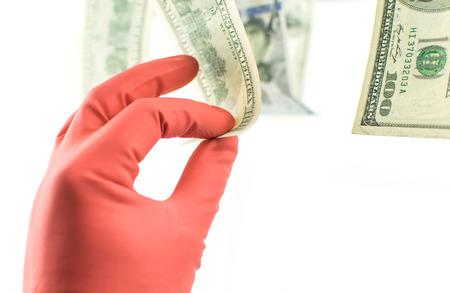 A hand in a rubber glove removes 100 dollars, which hang on the clothespin on a white background.の写真素材