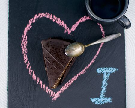 Chocolate cake and a cup of coffee on a stone plate with a heart painted on it.の写真素材