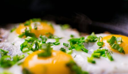 Fried chicken eggs with greens and spring onions in a frying pan.の写真素材