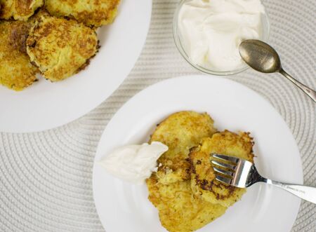 Fried potato pancakes on a white plate and sour cream.の写真素材
