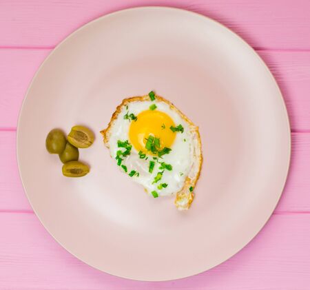 Fried chicken eggs with greens and green onions on a pink plate.の写真素材